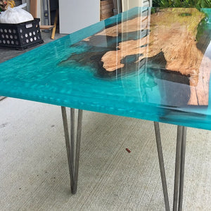 Aqua colored table top epoxy resin river table with metal legs.
